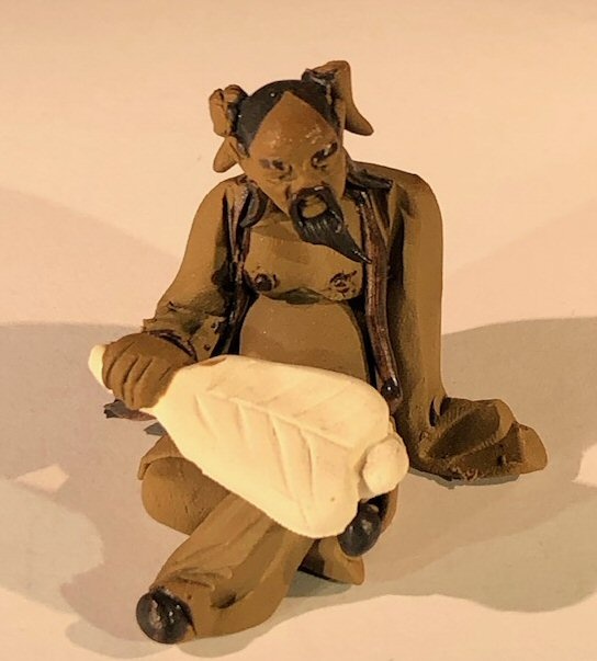 Ceramic Figurine Mud Man Holding A Fan Sitting Down - 2"